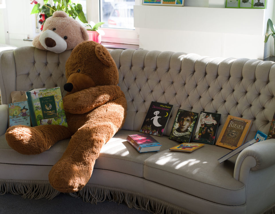 Blick ins Bilderbuch-Café mit lesendem Teddybär auf dem Sofa.